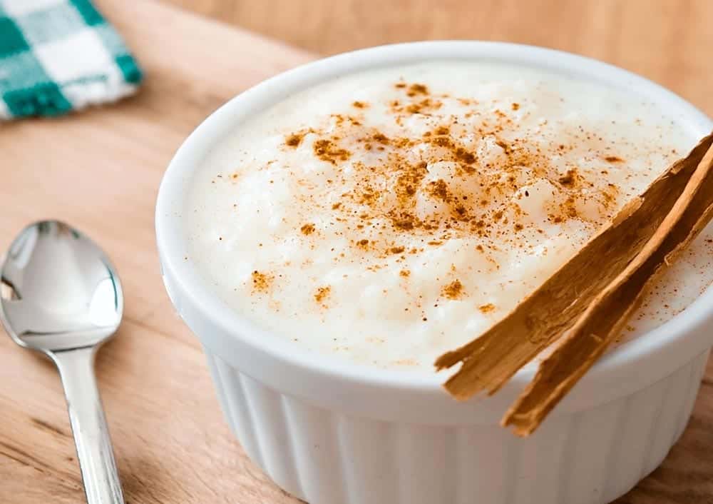 Tigela de canjica cremosa com canela em pó.