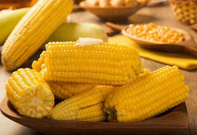 Espiga de milho cozido com manteiga derretendo.