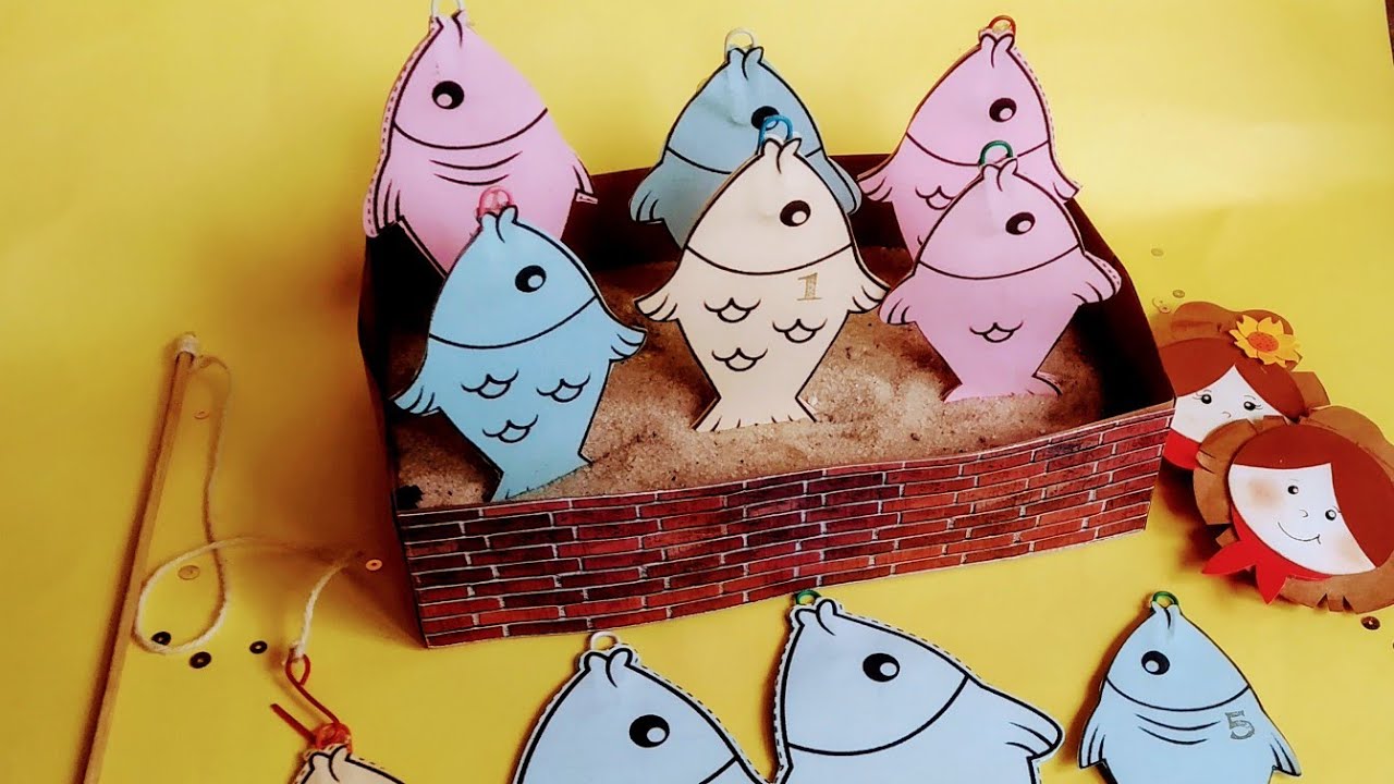 Crianças brincando de pescaria com vara e peixes de brinquedo.